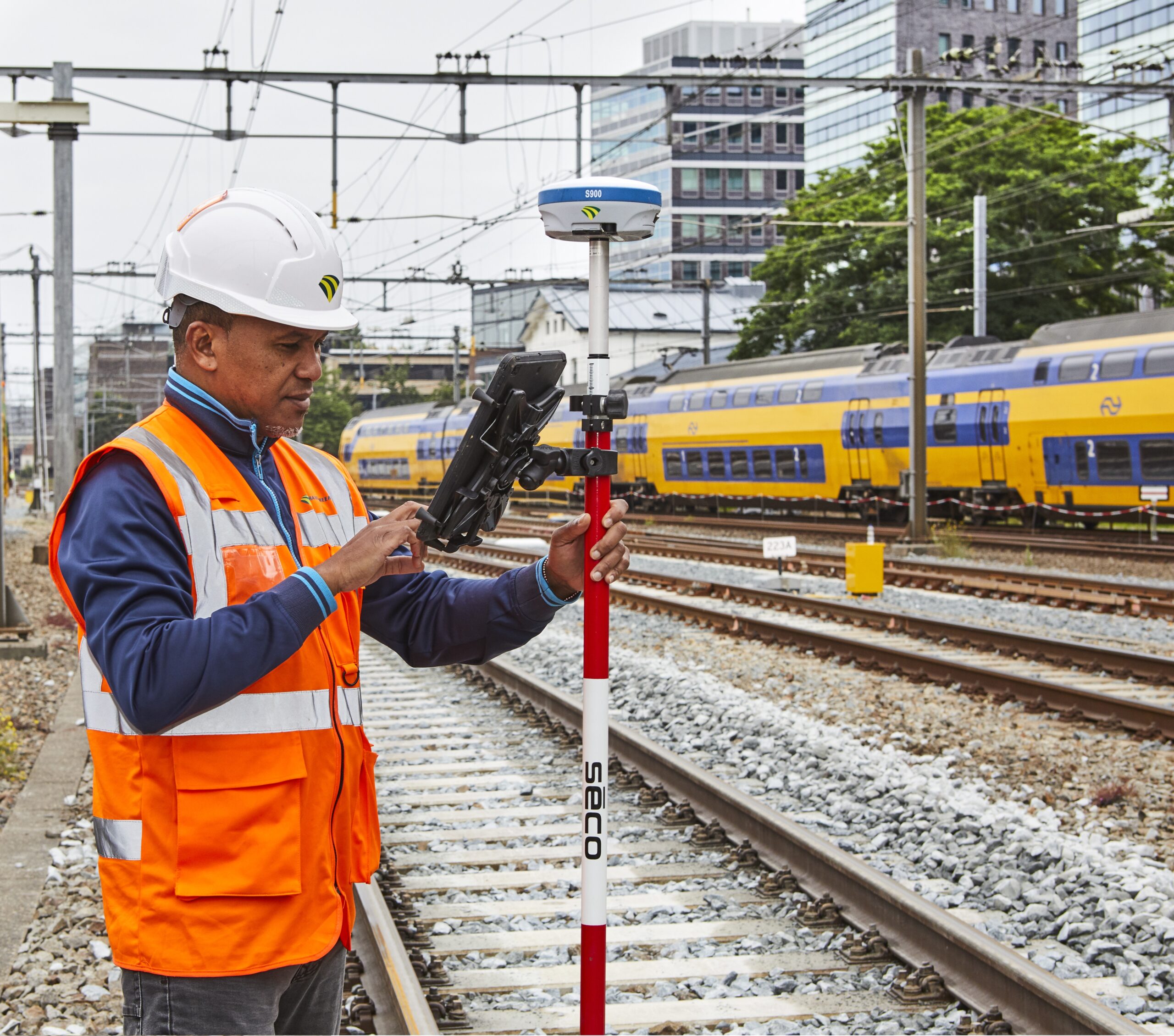 Monteur met meetstok langs spoor